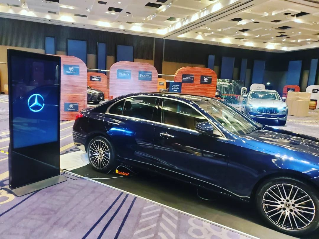 Tótem digital con logo de Mercedes-Benz junto a auto en exhibición